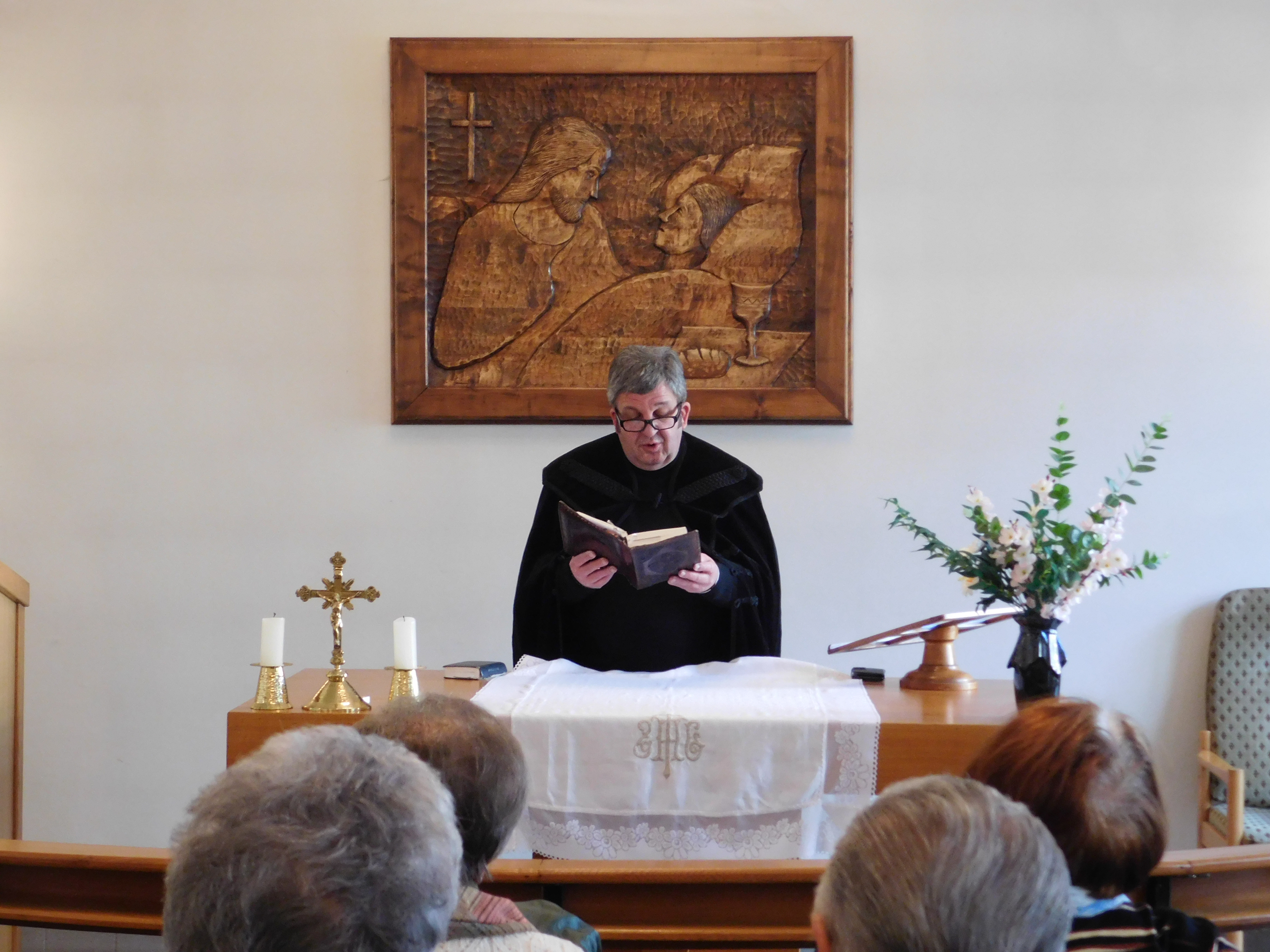 Egy pap közönség előtt felolvas egy könyvből
