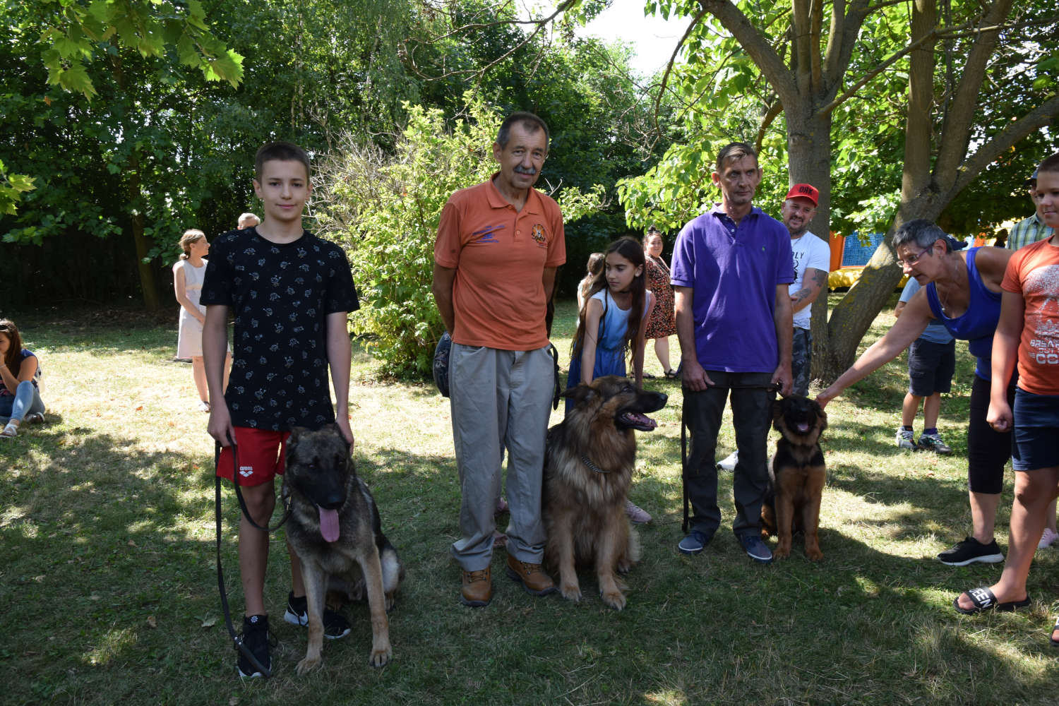 Emberek állnak kutyáik mellett