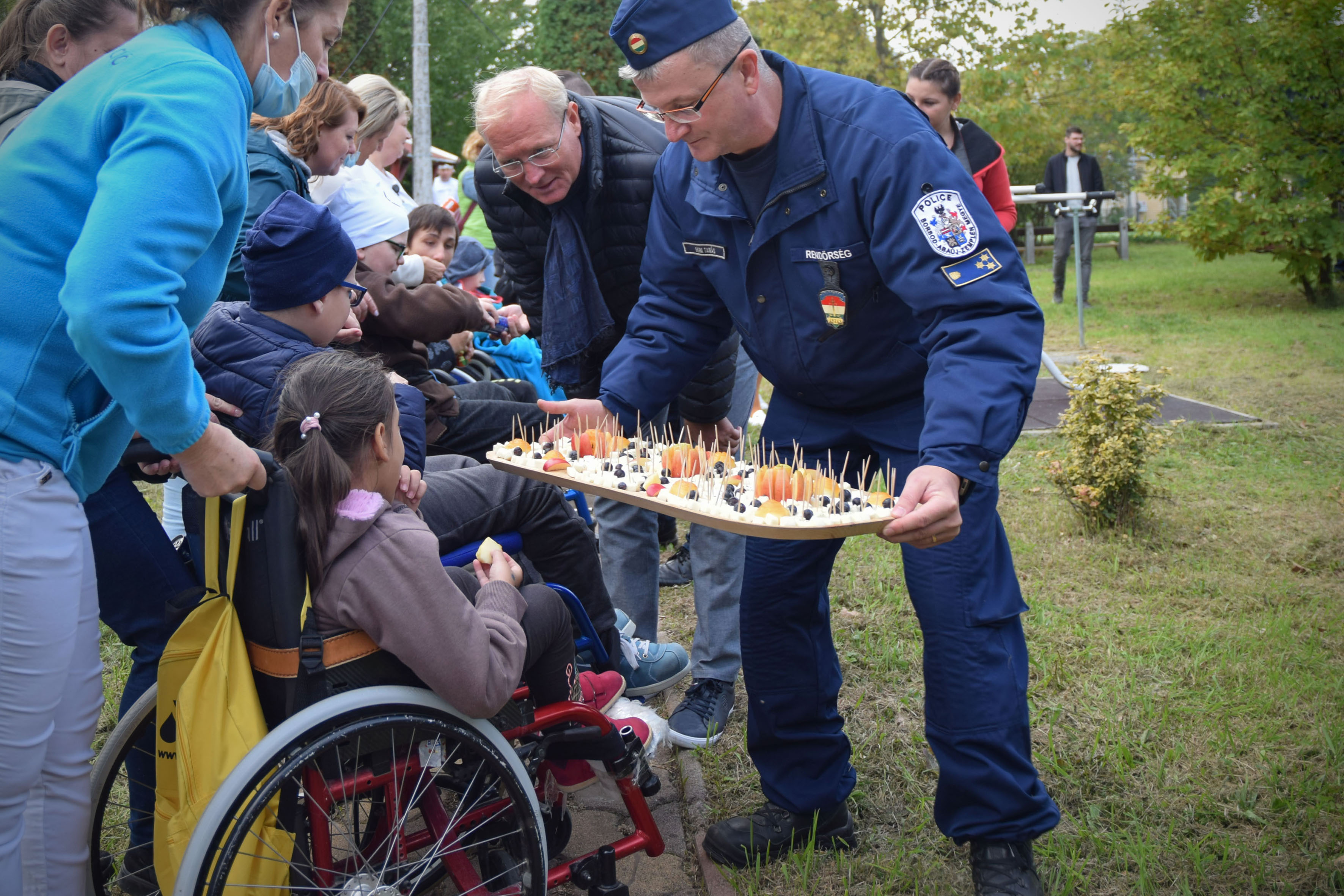 Egy rendőr tálcán sajtot osztogat egy kerekesszékes lánynak