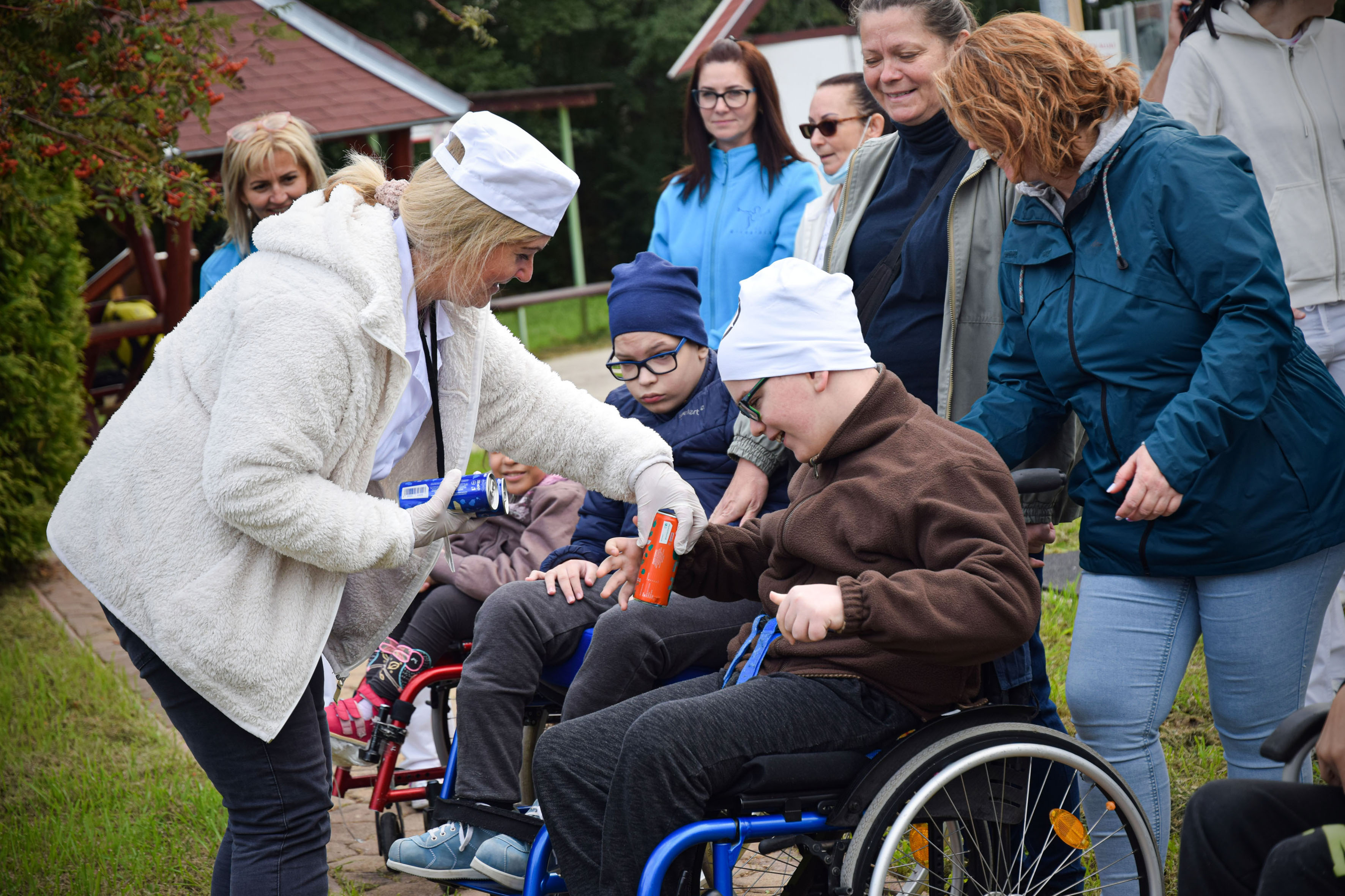 Dobozos üdítőt nyújt át egy hölgy egy kerekesszékes fiúnak