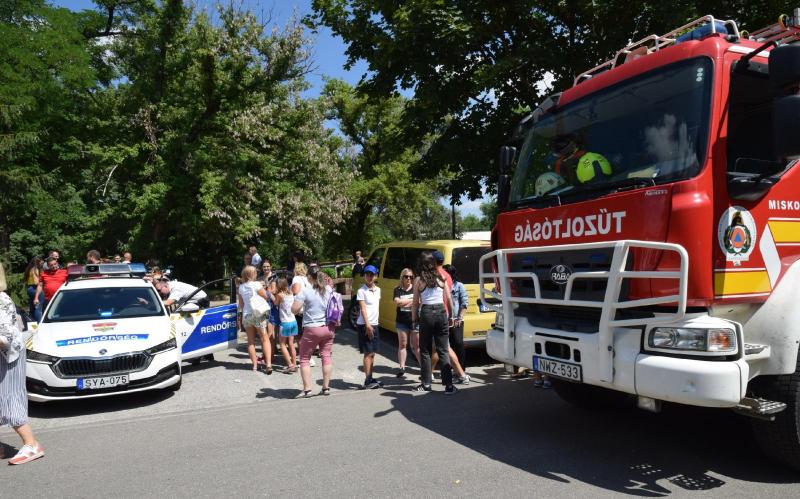 Ember állnak rendőr és tűzoltó autó között